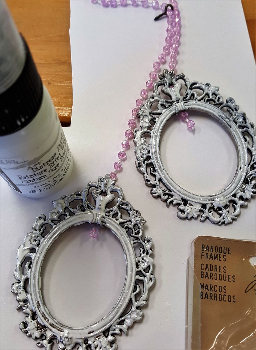 I painted the Idea-Ology frames with white prickle fence distress paint. Then, I glued the bead-strings to the back to add some pictures.