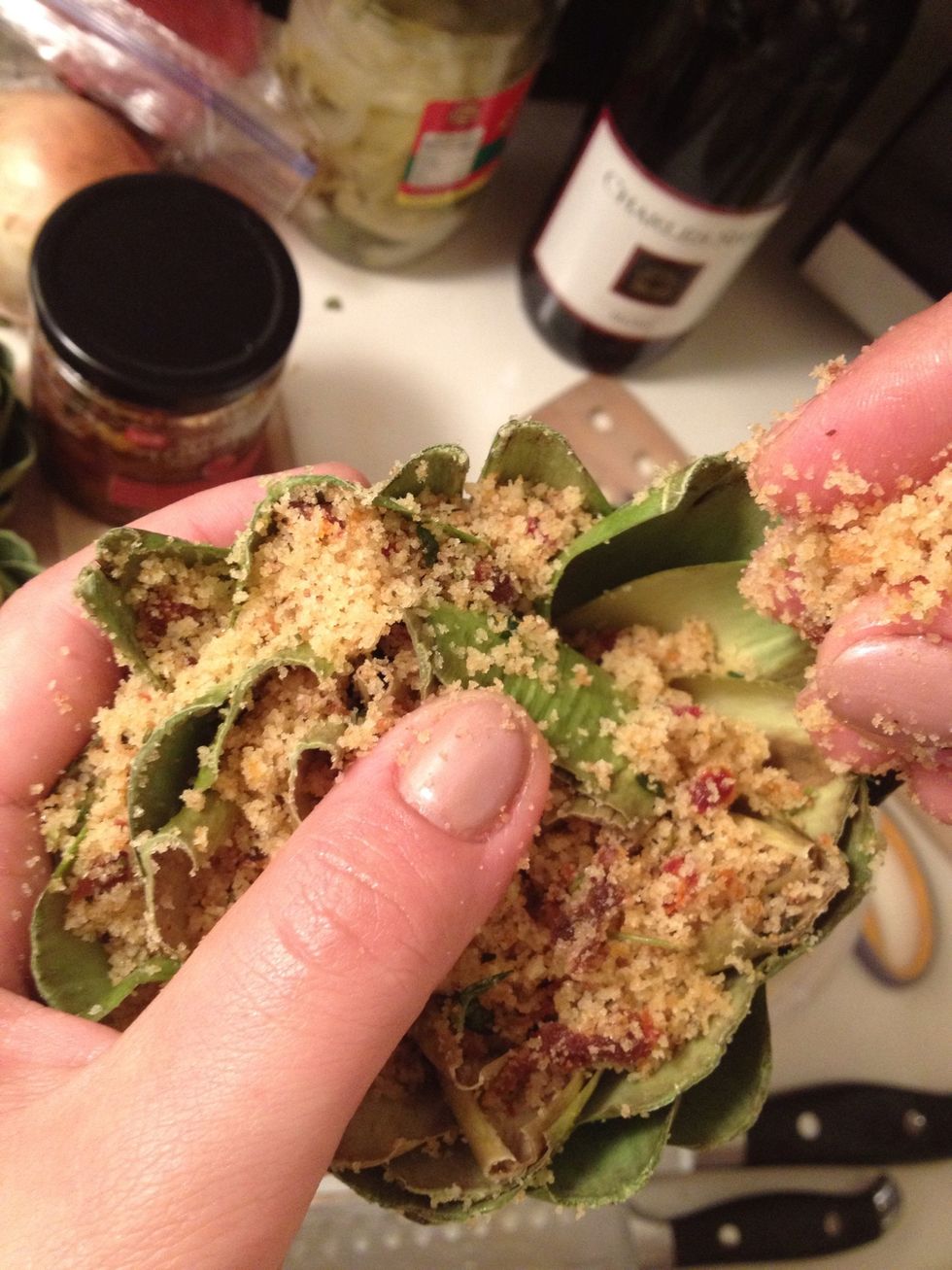 I start by stuffing in the middle of the artichoke and then spreading the leaves open and adding more crumbs to each leaf.