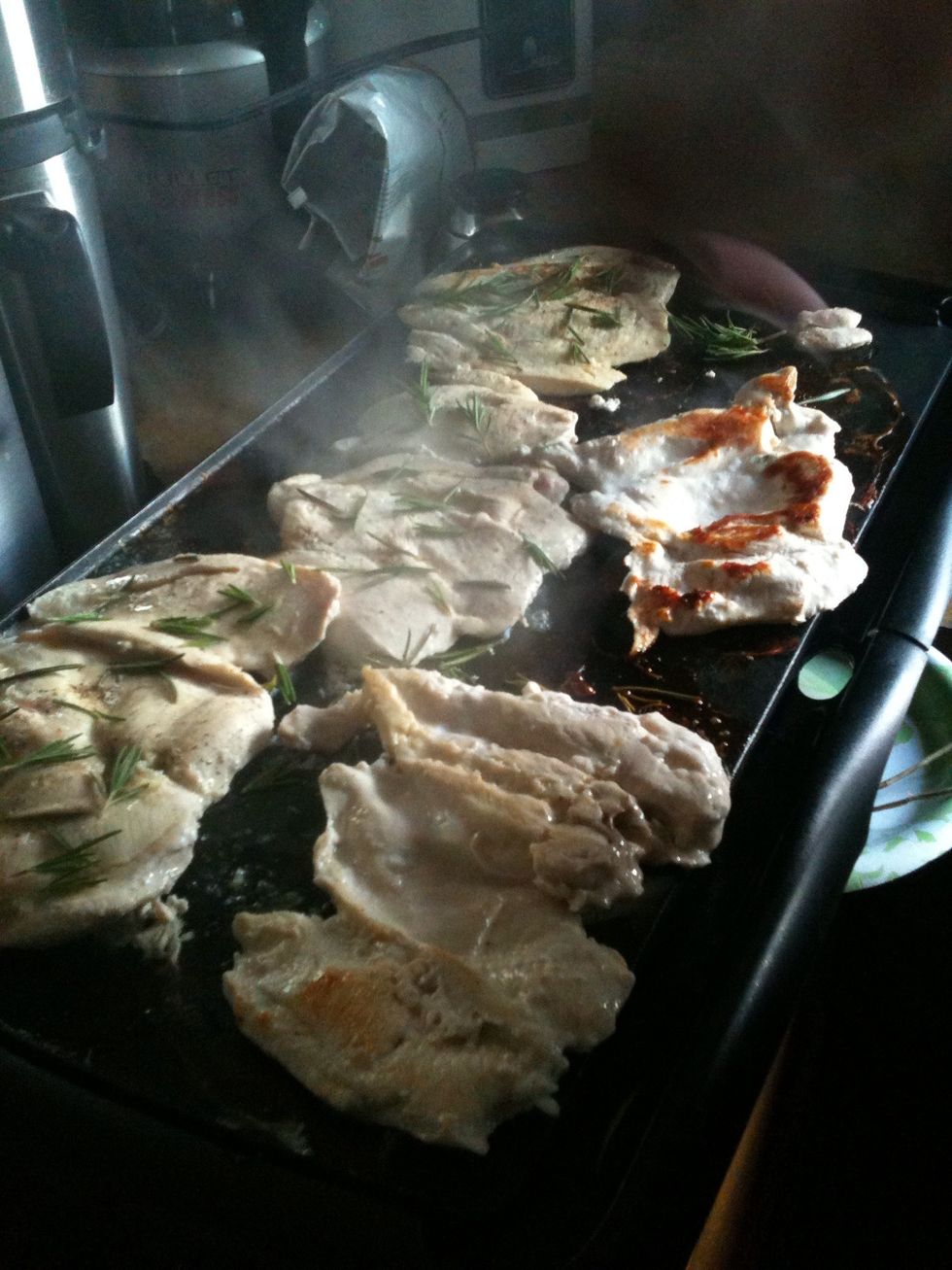 I started by brushing off some rosemary pieces and putting them on the grill, then flipping the chicken, and then putting our slightly caramelized rosemary on the already cooked chicken side