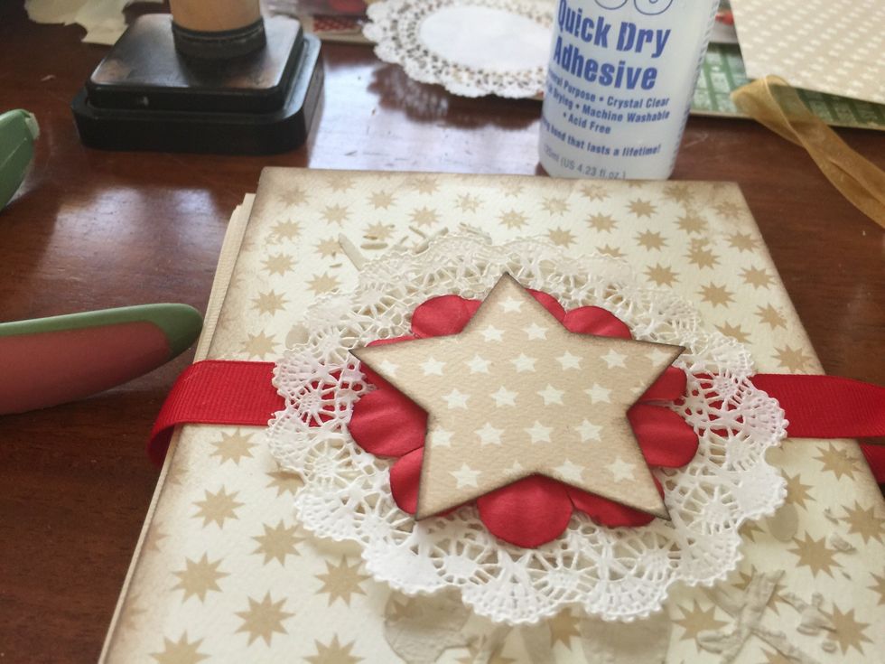 I started layering the elements for the cover. Doily, large star punch and a flower! Glue the ribbon across the front leave a little slack around the spine (for expansion) and glue on the back.