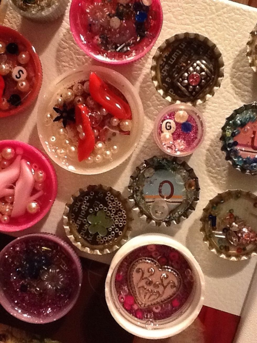 I turn them onto an old cookie sheet so that the magnet keeps the cap in place...while the fun part continues!   Fill each magnet with paper scraps, glitter, beads, buttons, small charms, rhinestones.