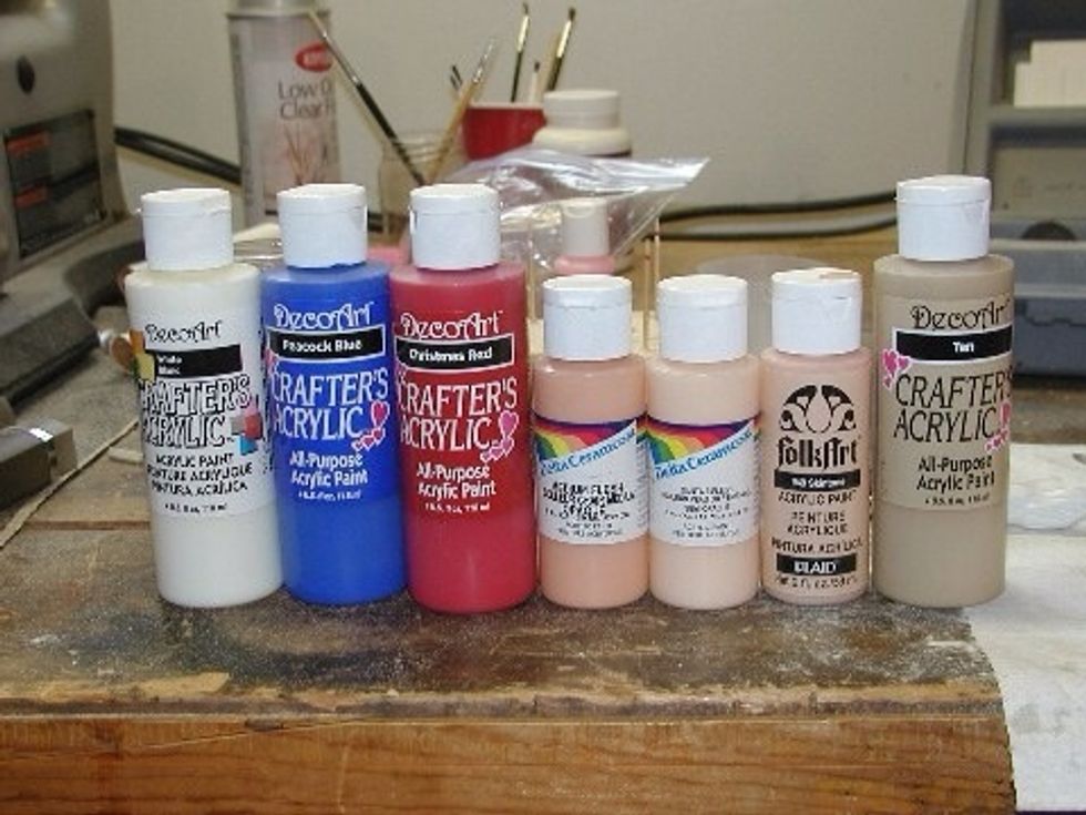 I use acrylic paint I get at the craft store.  It is quite cheap and there is a multitude of colors.  It covers in one coat.  You may have to mix the flesh tone to get it right.