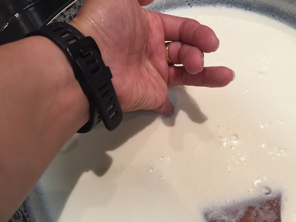 I use my pinky to feel the temperature. Stir the milk so the temperature is even then use your pinky. If you can hold your finder in it without feeling burnt, it is the right time.