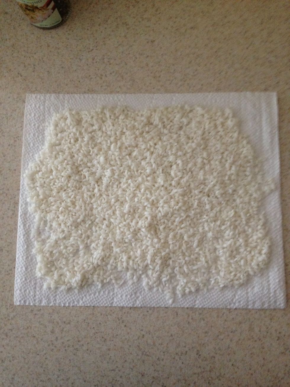 I use paper towel, but the rice WILL stick to the towel a little. I think a strainer would be the best way to go. The one we have has holes too big so the rice would slip thru.