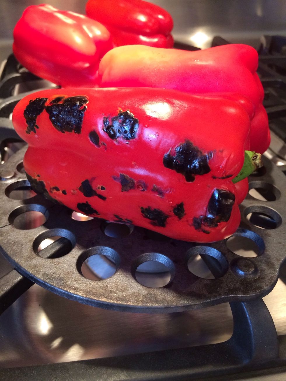 I used a cast iron open grate trivet to fire roast my peppers. Turn the peppers often to make sure they are burnt evenly. Don't be afraid of burning the peppers, this is what we want to do here.