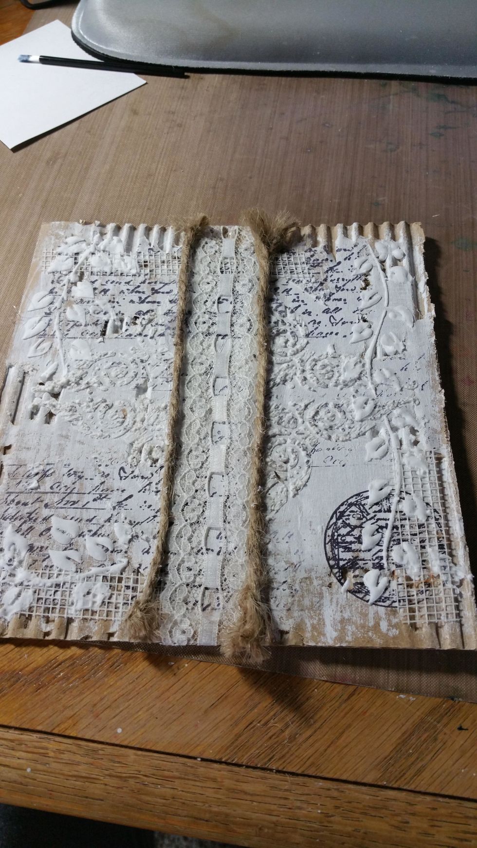 I used another stencil to add another layer using texture paste. A piece of antique lace was tacked in the middle and outlined with two strips of jute rope.