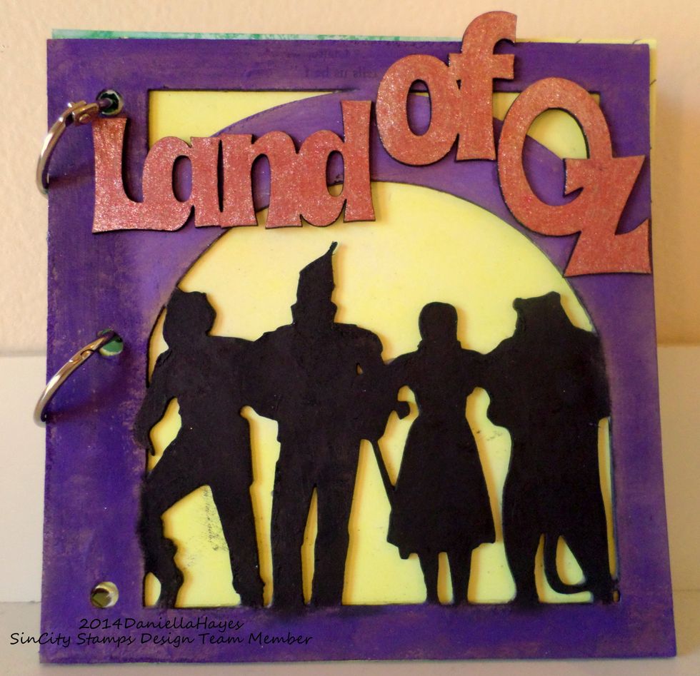 I used Purple Pan Pastel around the outside. I used glitter markers on the letters. I colored a piece of paper with yellow Pan Pastel and attached it behind the cover.