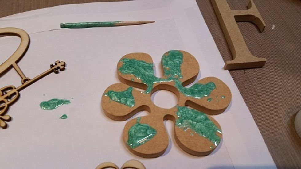 I've used a toothpick to blob the emerald paint on this wooden flowers first.