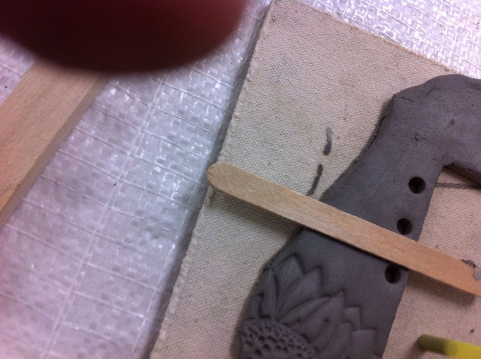 If using as a loom, line up a Popsicle stick with the edge of the opening and use a straw to poke a hole in the frame.