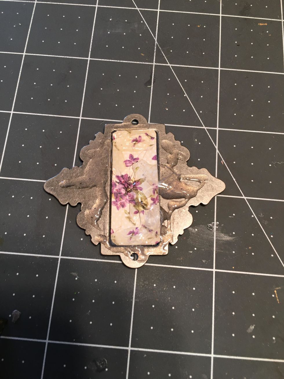 If you add a metal label holder to your project, cut a small piece of patterned paper for the label and apply 3-in-1 glue to the back of the label holder as shown.