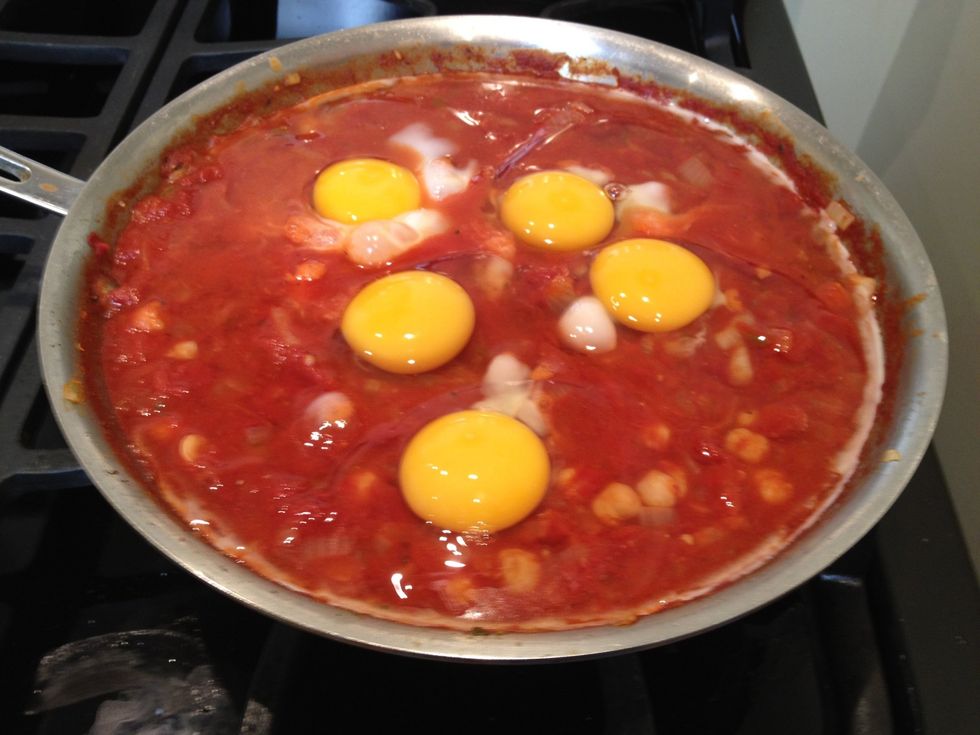 If you want to add feta, sprinkle it on now. One of my guests does not eat cheese, so I will put it on individual servings at the end. Then crack the eggs on top. Be sure not to break the yolks!