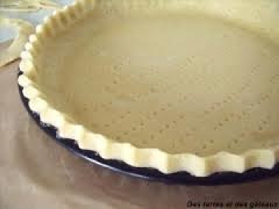 Il faut tout d'abord \u00e9taler la p\u00e2te dans le moule et ensuite il faut la couvrir d'un papier sulfuris\u00e9 et d'haricots. Mettez \u00e0 cuire 10 minutes.