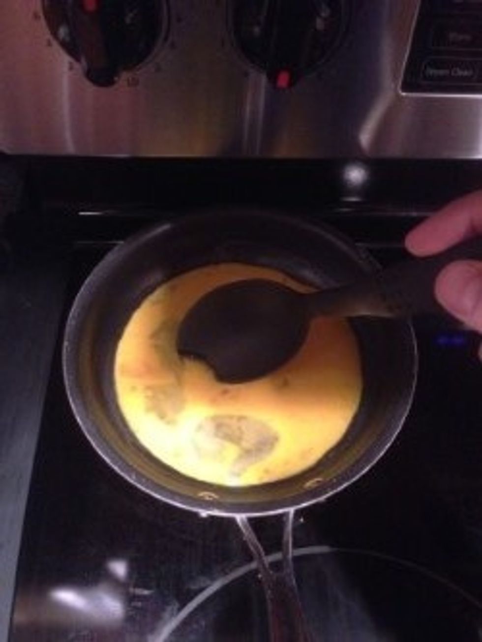 Immediately, pick up the plastic spoon and begin stirring the scrambled eggs