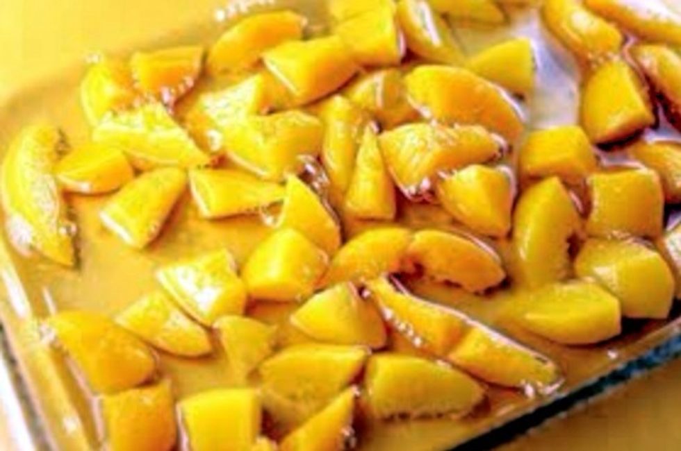 In a 9 by 13 inch glass baking dish dump your can of peaches and syrup. Cut the peaches in halves to cover the whole dish evenly.