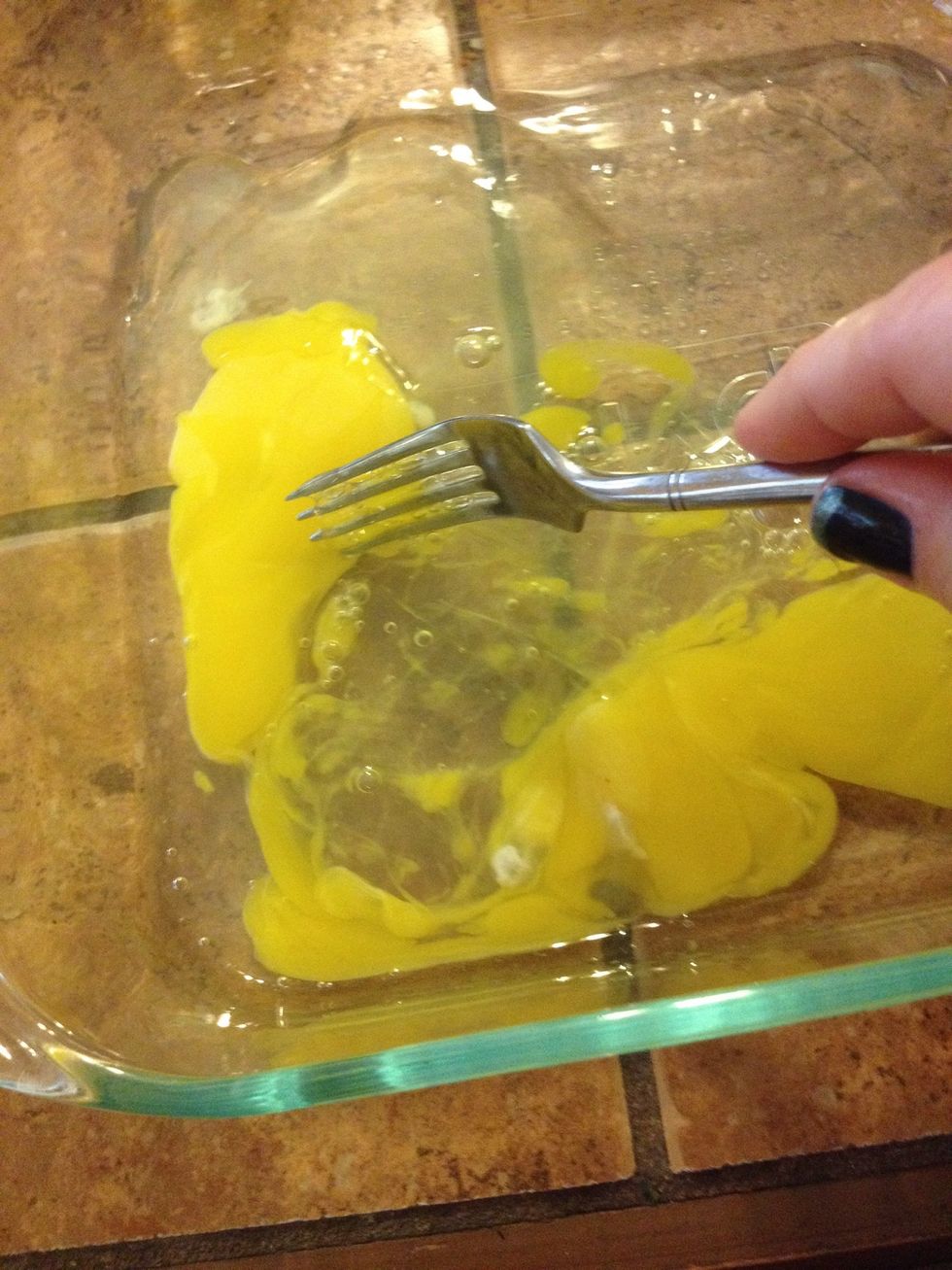 In a casserole dish, scramble two raw eggs.