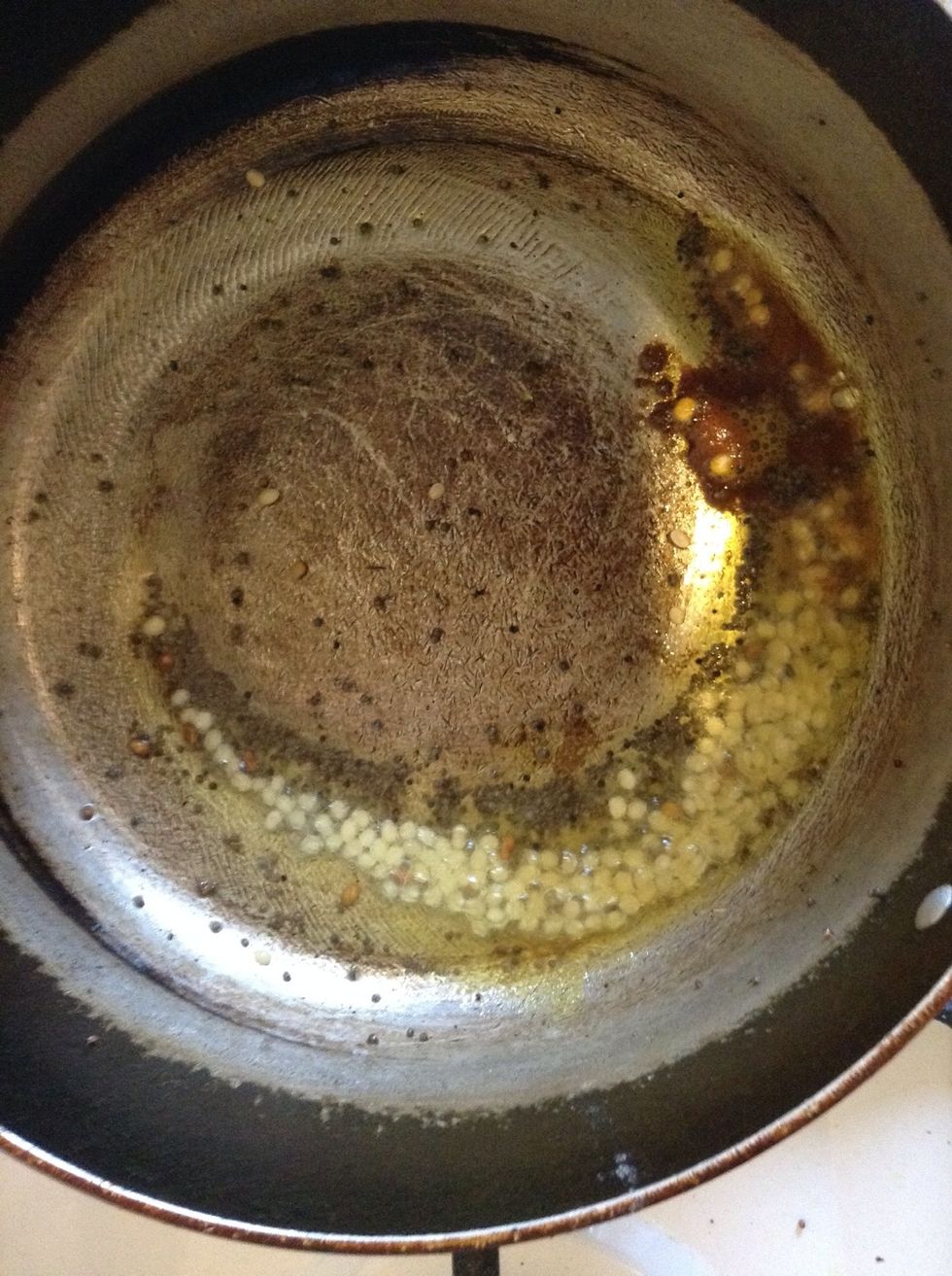 In a cooking pan, heat some oil. Then add turmeric powder, mustard seeds, fenugreek seeds, asafoetida and urad dal. Wait until the urad dal starts turning red.