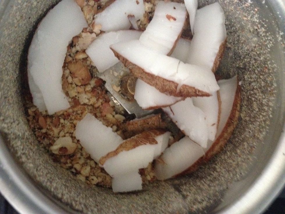In a grinder put peanuts and coconut