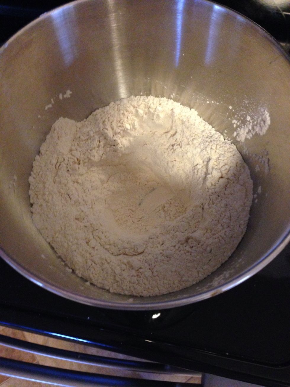In a large bowl, mix together the flours and salt. Create a well in the middle and pour yeast sugar mixture. Pour half of the remaining water into the well and mix.