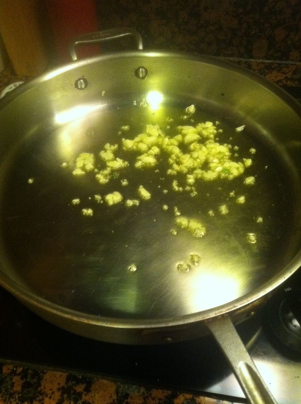 In a large saut\u00e9 pan, lightly saut\u00e9 the garlic in olive oil.