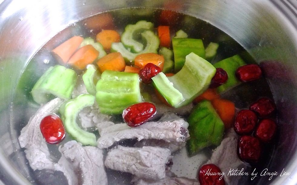 In a large soup pot, add in 2 litres of water. Bring to a boil. Then add blanched pork ribs, red dates, carrot and large bitter gourd chunks.