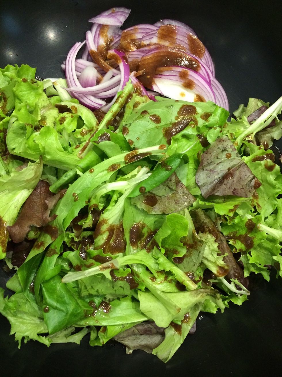 In a mixing bowl, put the greens and the onion. Drizzle the dressing