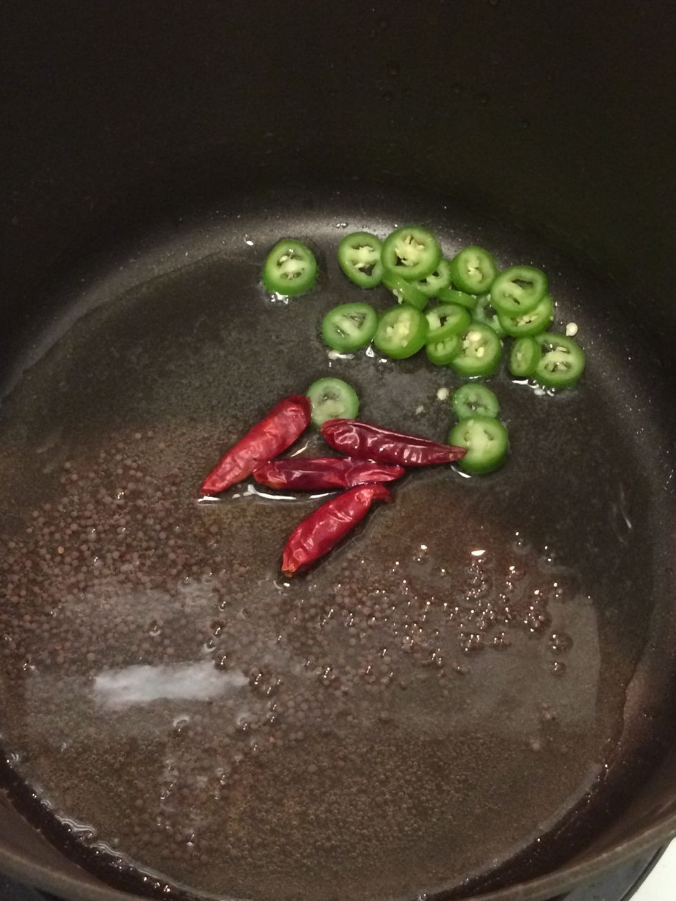 In a non-stick pot over medium heat, add oil. In about 2-3 min. add asafoetida, black mustard seeds, serrano chili pepper and the Japanese chili pods. Allow for the mustard seeds to pop.
