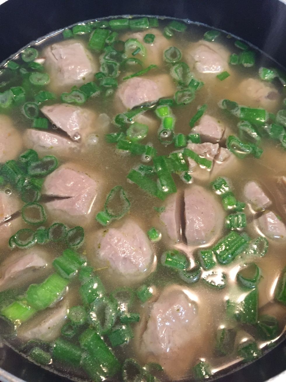 In a pot, boil chicken stock and add meatball, splash of sesame oil, and green onion in it.