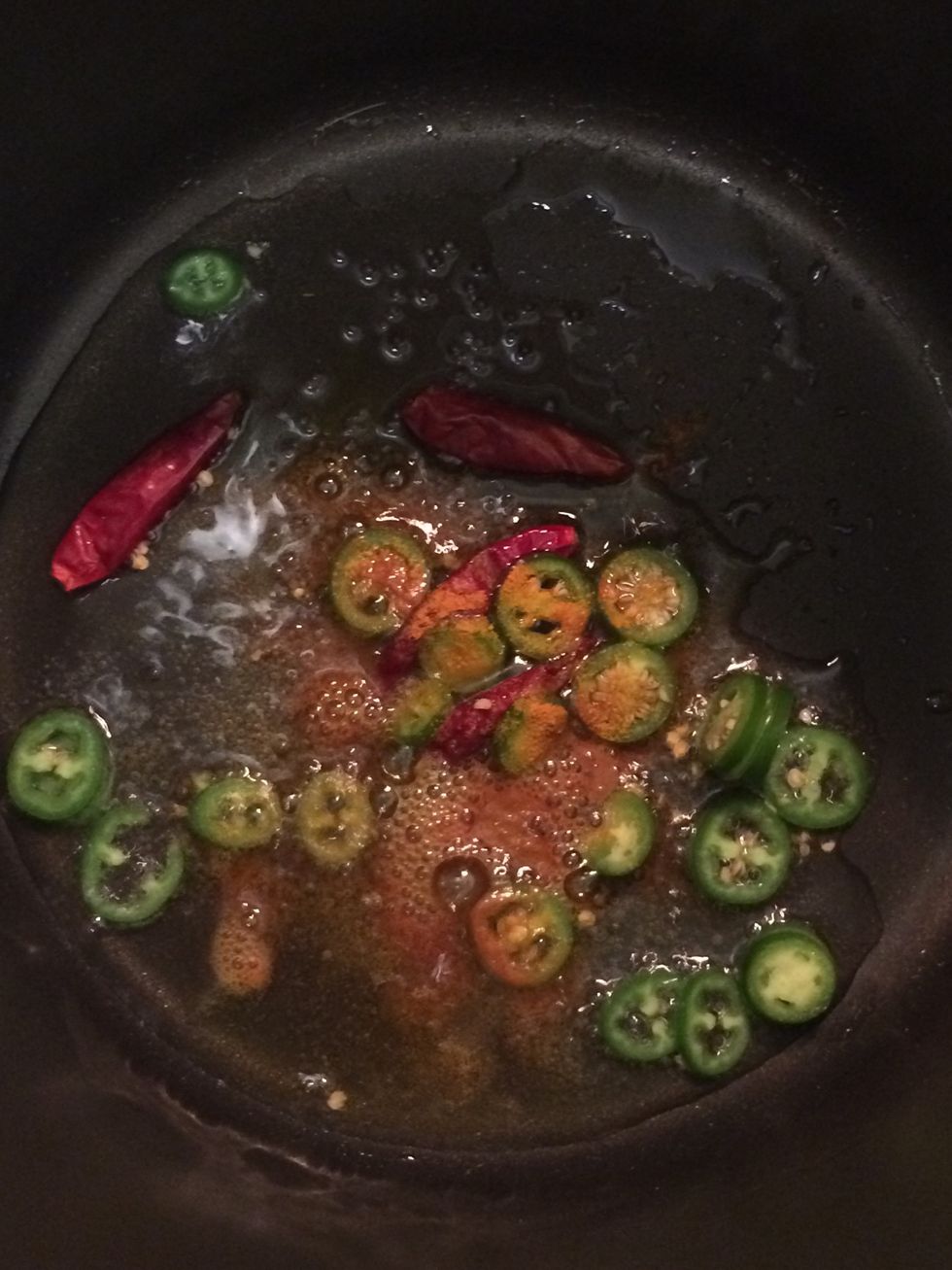 In a pot over medium heat, add oil. Once the oil heats up, add asafoetida, Japanese chili pods, mustard seeds, serrano chili pepper and 1/2 teaspoon of ground turmeric.