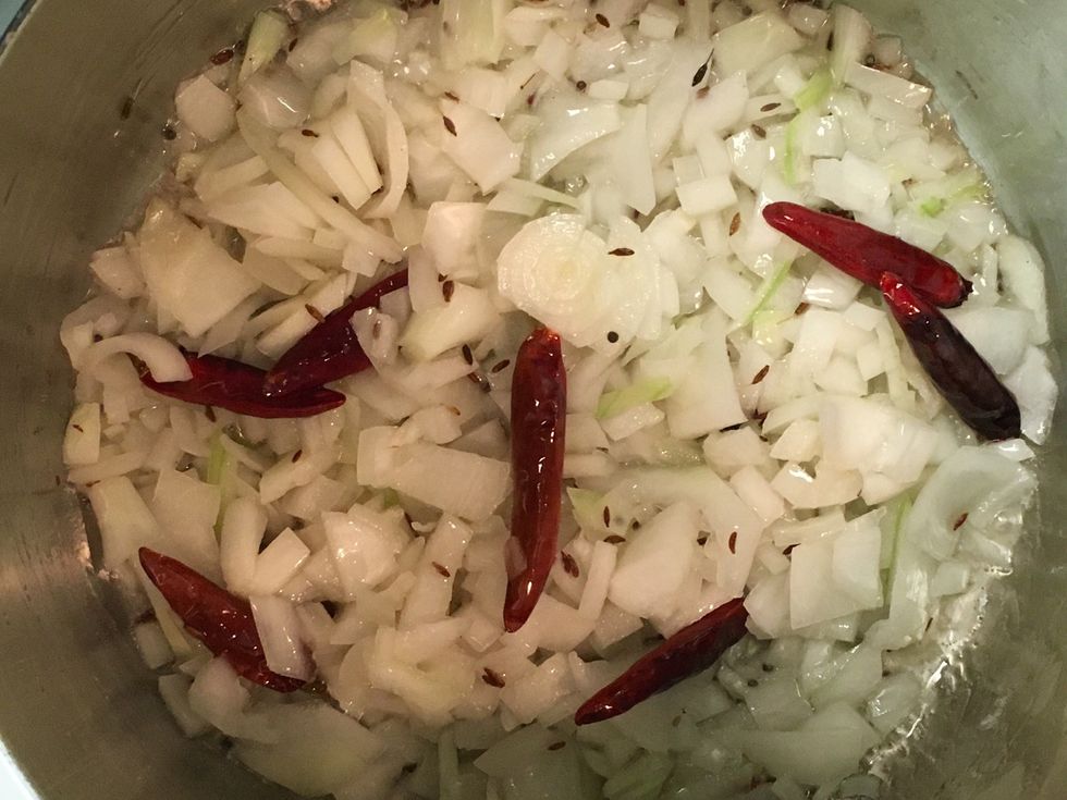 In a rondeau pan over medium heat, add oil. Once the oil heats up, add asafoetida, black mustard seeds, red chili pods and whole cumin. In about 2 mins. add onions and saut\u00e9.