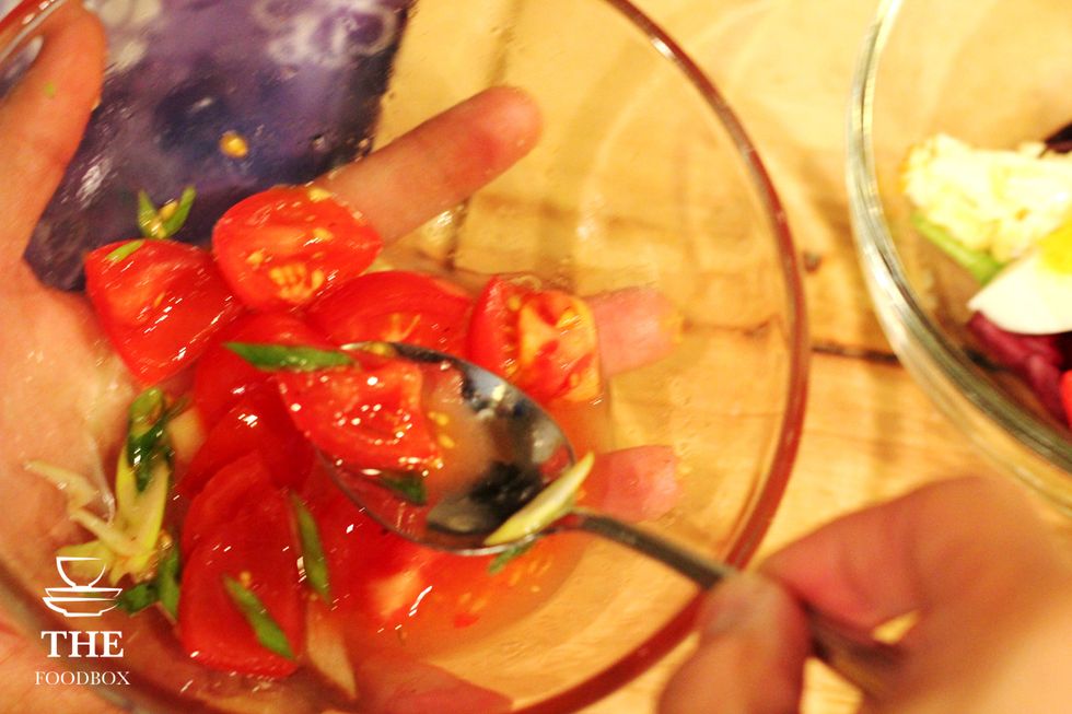 In a separate bowl, add your tomatoes and some sliced green onions. Make sure to season with salt and pepper, and add about a tsp of sesame oil, and add about a tsp of olive oil.