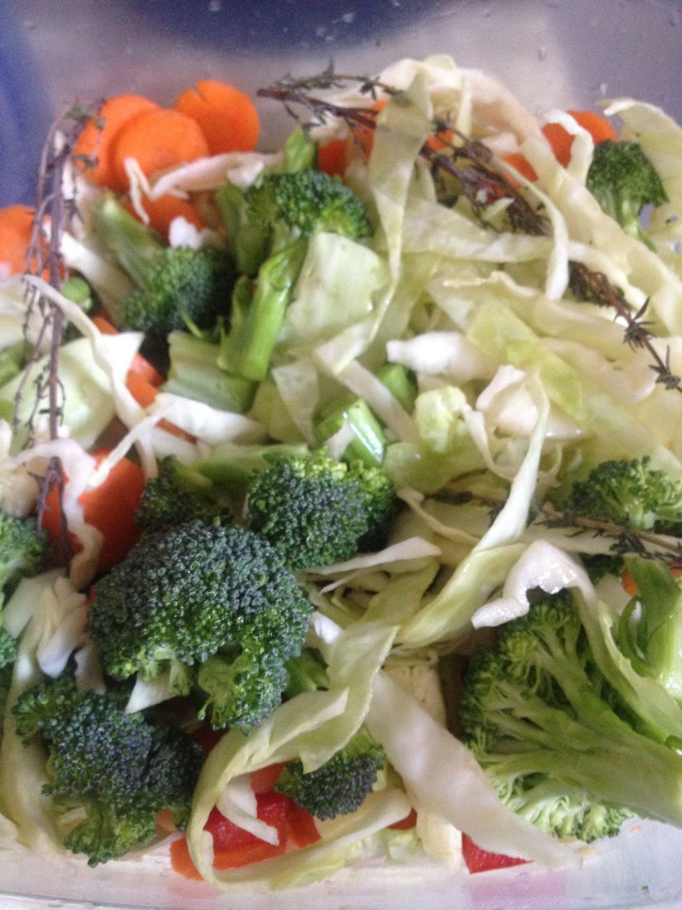 In a separate container, combine cabbage, broccoli, onion, garlic, thyme, sweet peppers, small piece of hot peer, carrots and drizzle with small amount of oil.