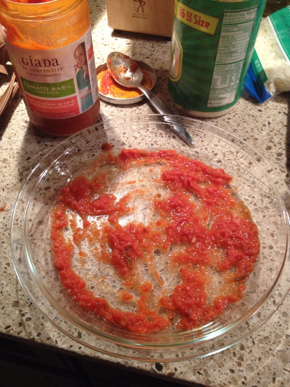 In a shallow dish, place down about a quarter cup of tomato sauce. I am using Giada's tomato basil sauce.
