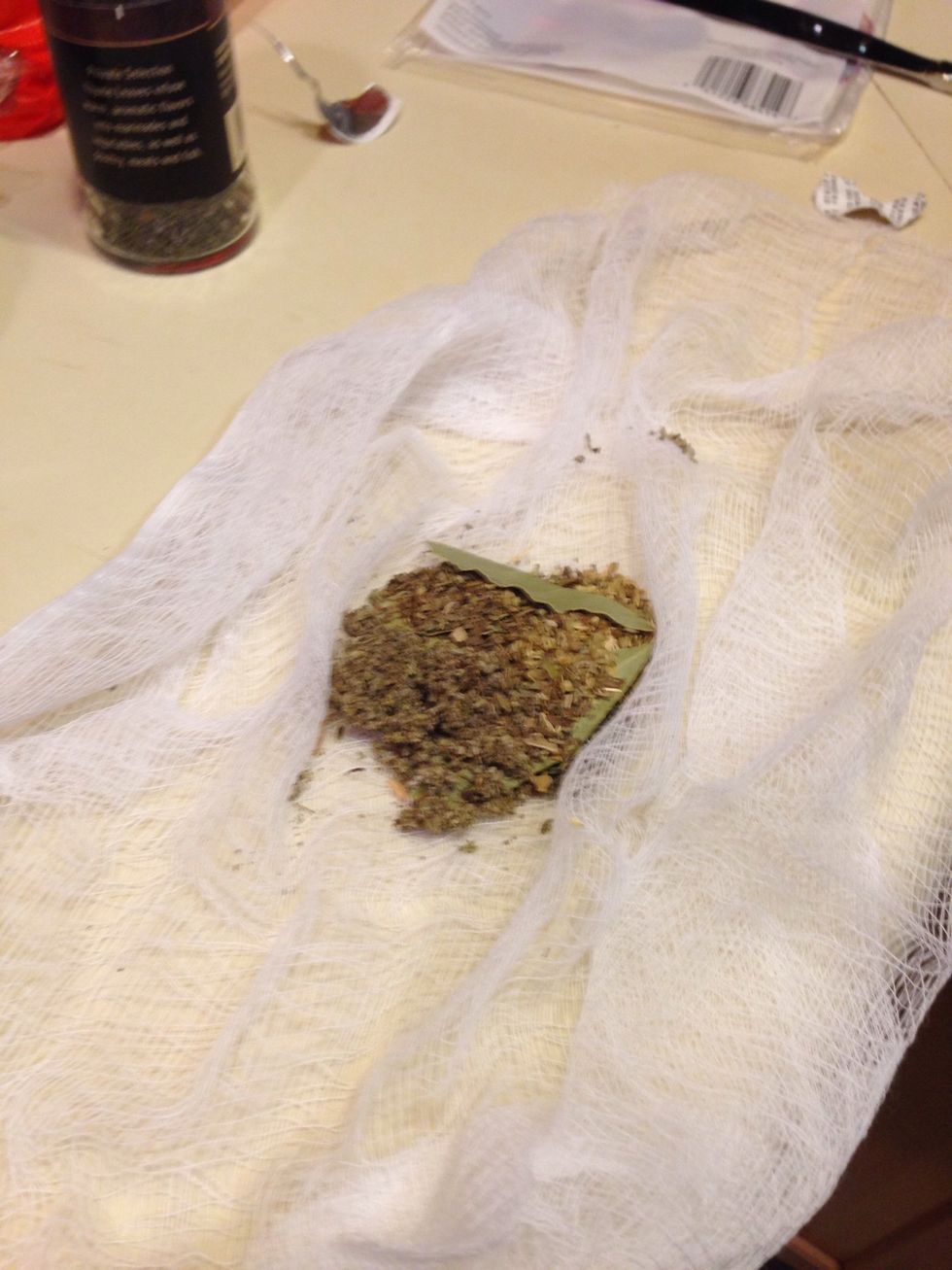 In a small peace of cheese cloth add the time, basil, oregano, and bay leaf. Then fill the stock pot full of water. And add the spice sack to the pot. Add some garlic to the pot.