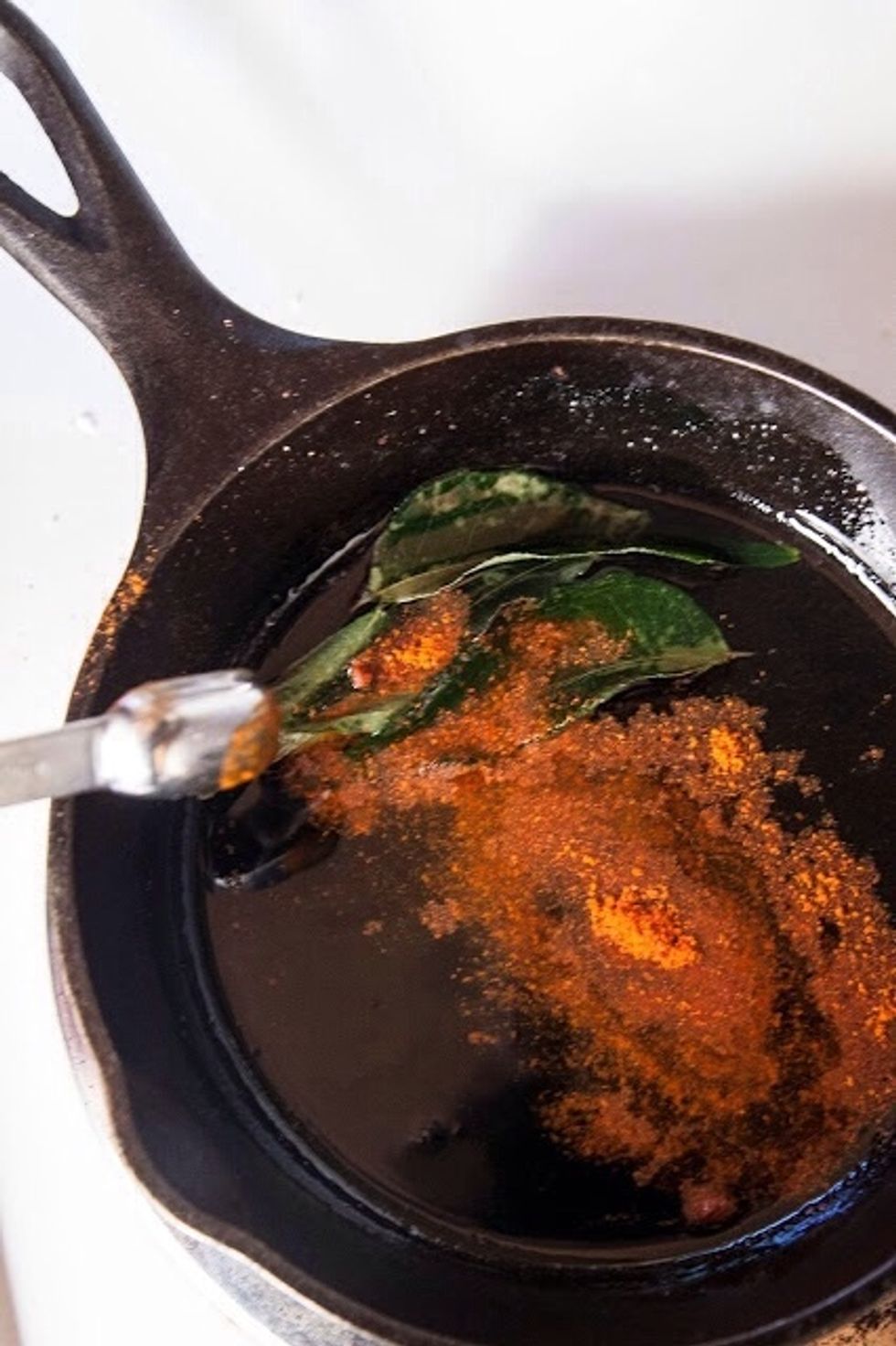 In a small skillet heat 1 Tbs of vegetable oil. When the oil has heated slightly, add in the curry leaves (if you have them) and the Kashmiri chili.