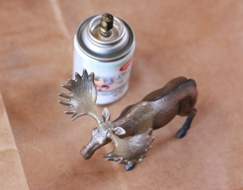 In a well-ventilated area and over a protective covering, apply thin and even coats of spray paint onto the plastic toy and wooden plaque. Allow each layer to dry before applying the next.