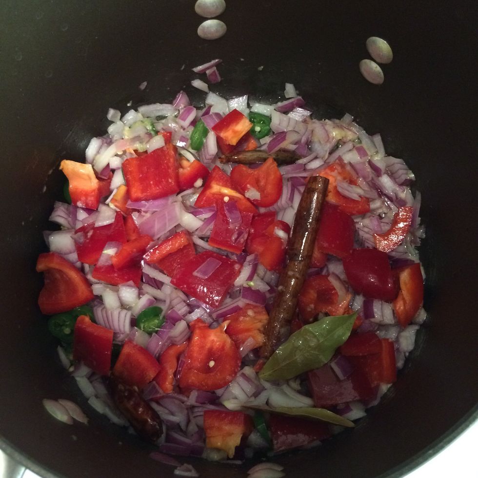 In about 2 minutes; with a fresh aroma of spices in the oil; add the ginger and garlic paste, chopped serrano pepper, onion and bell pepper. Saut\u00e9 till onion becomes translucent.