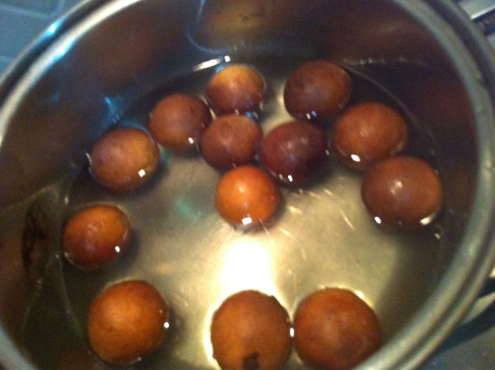 in another pan add water and sugar and heat.. dissolve sugar and further cook it for 2 min.. dont let it go thick.. make watery sugar syrup.. lower the heat to MINIMUM after 2 min and add you balls