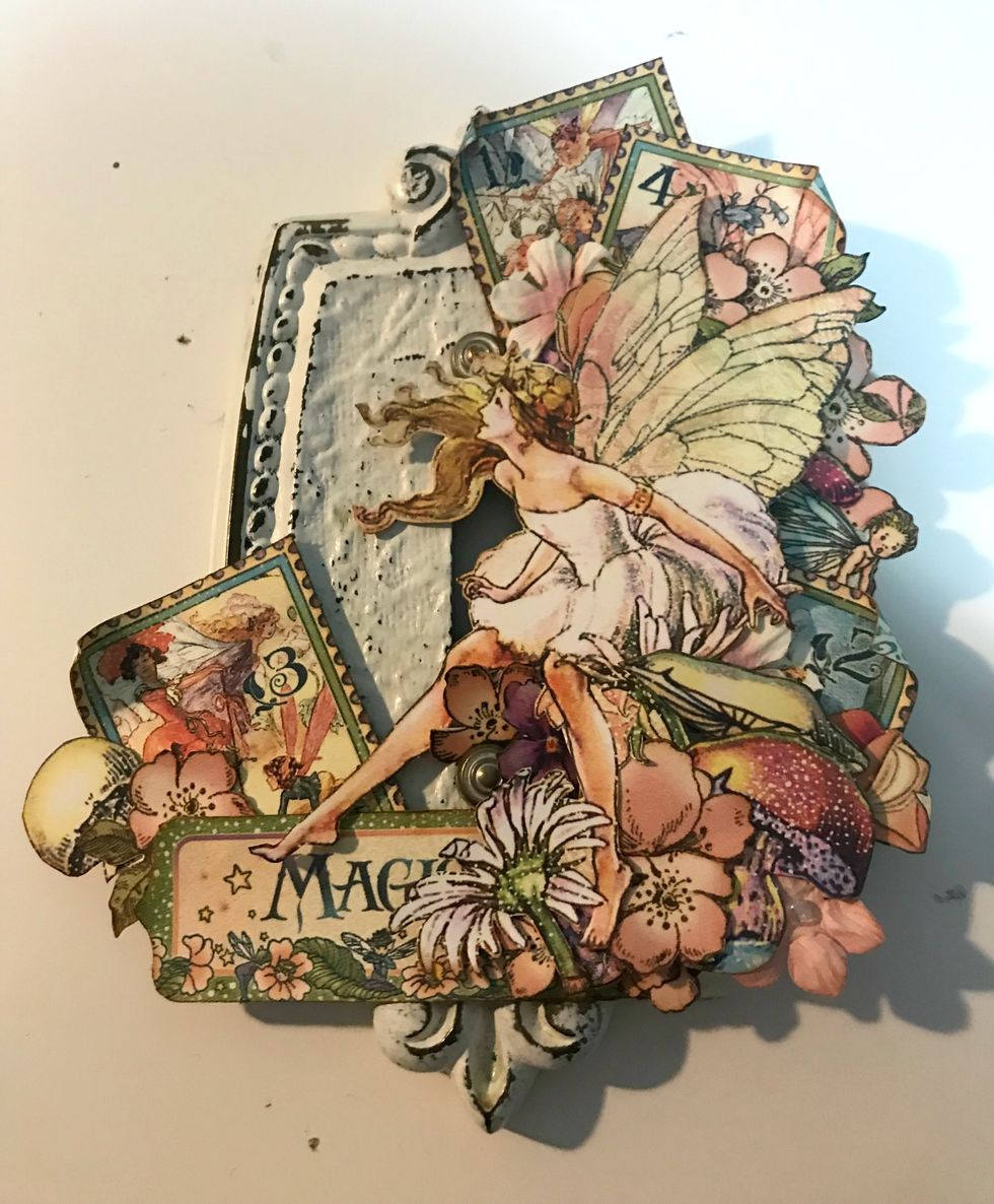 In behind the Magic tag, adhere a toadstool, a stamp and 1 single flower.  Roll down one of the corners on the stamp.