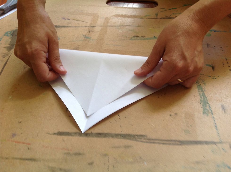 In order to find the center of the square, fold the square in half again. We want to make a folded "X" on our paper.