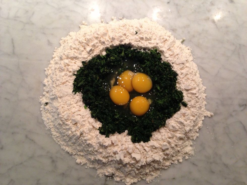 In that well, place your drained and chopped spinach, eggs and salt.