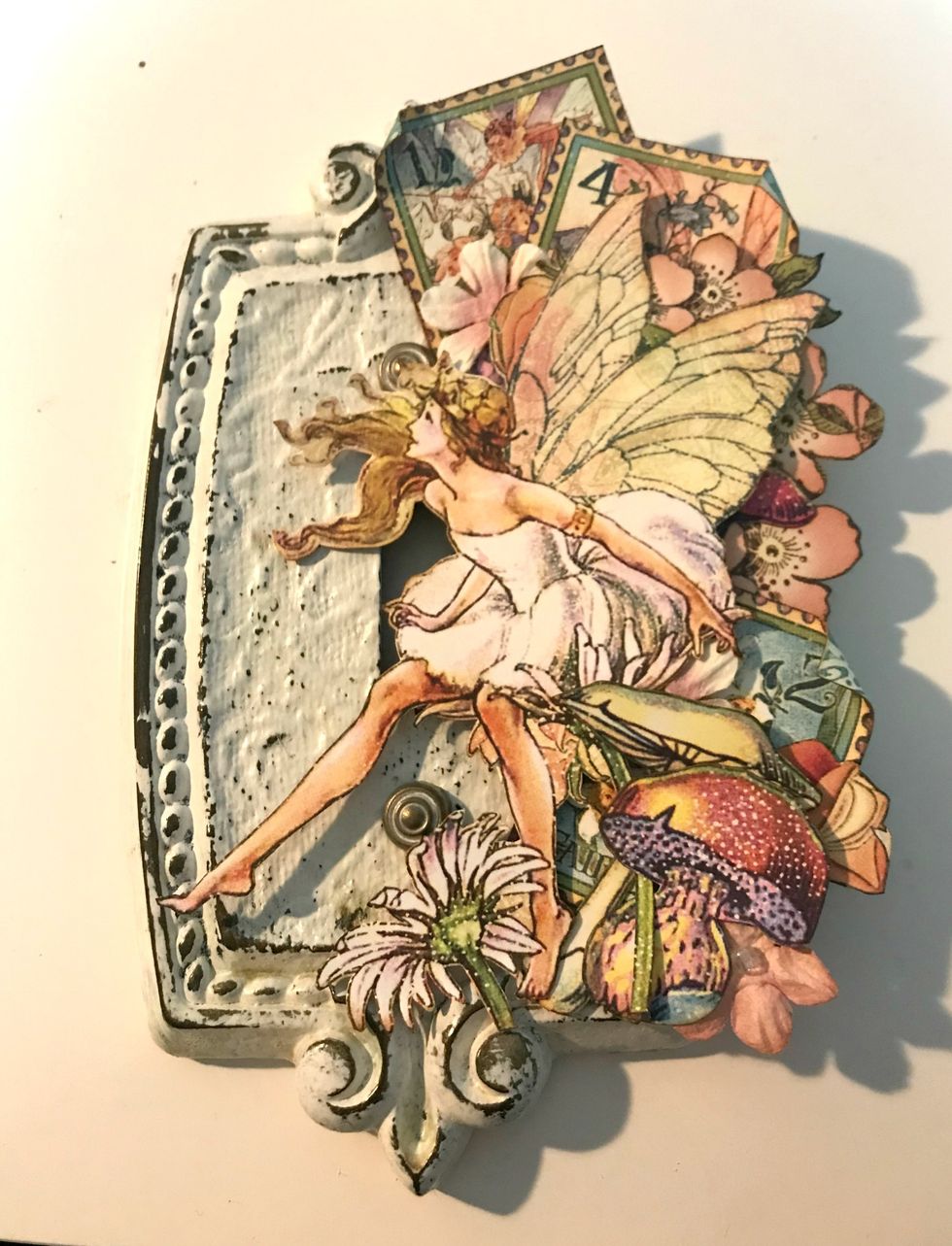 In the bottom right corner, adhere 1 coral flower, 2 toadstools &  2 daisies. Foam square the large fairy on the right side of the hole for the light switch.