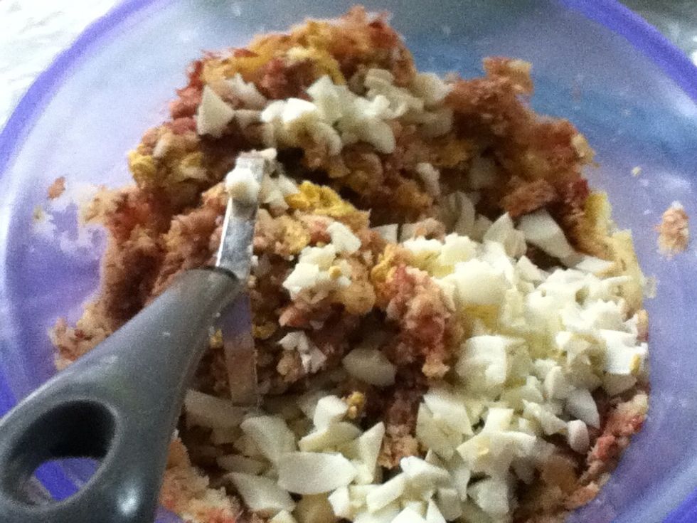 In the bowl of mashed potatoes mix chopped eggs and cooked meat. Mix them together.