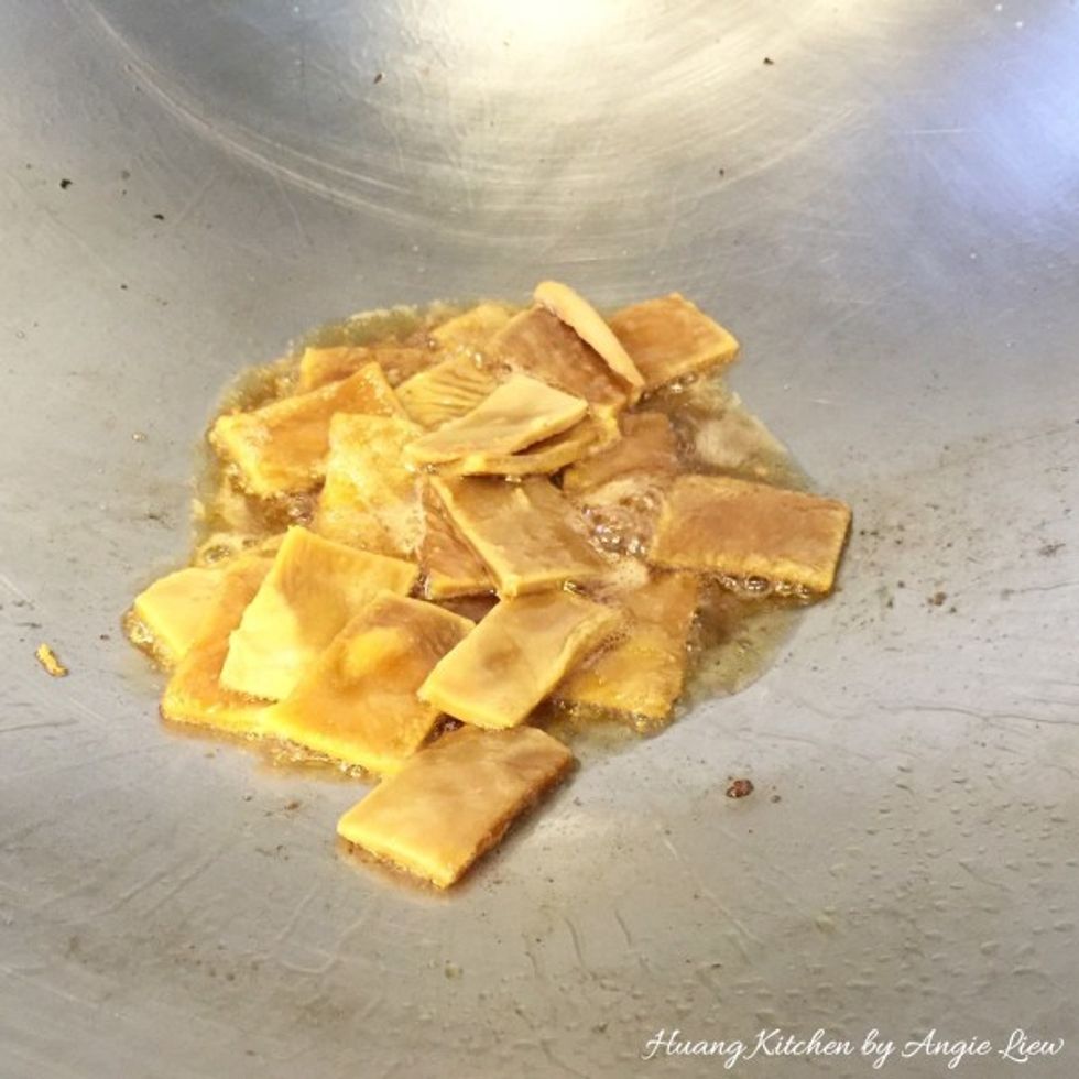 In the same wok, heat up another tablespoon of sesame oil. Add in the dried sweet beancurd strips and stir fry the beancurd in the oil until slightly browned, about 3 minutes.
