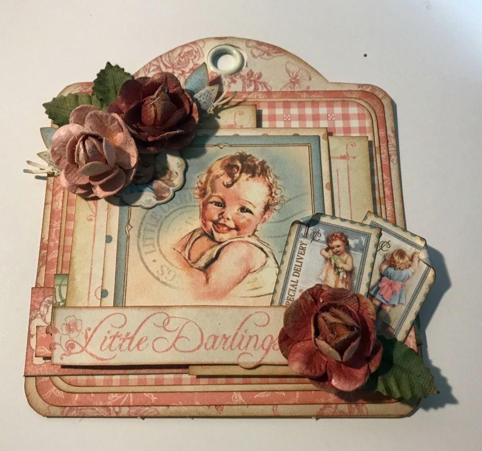 In the top left hand corner of the baby image, adhere two flowers, the two butterflies and the baby holding the teddy bear image.