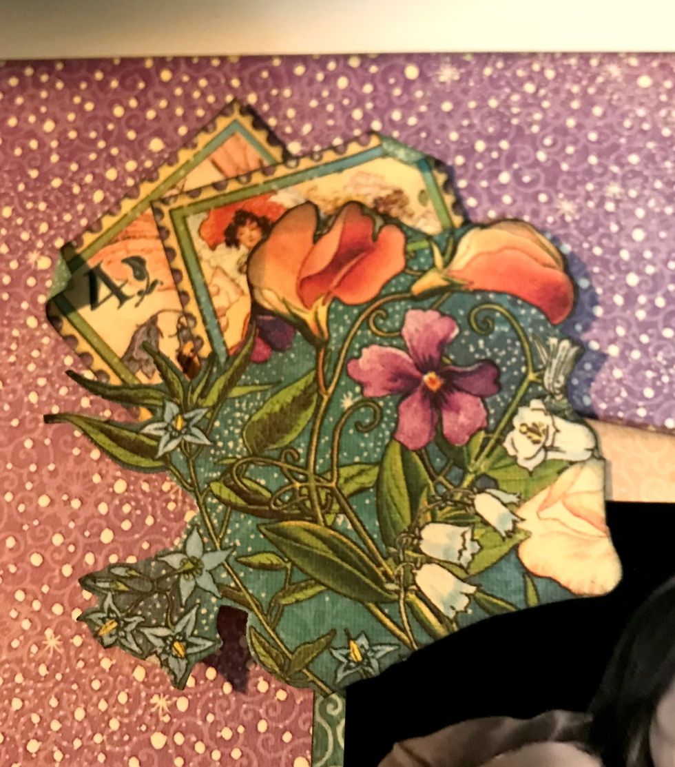In the top left hand corner of the photo, adhere two stamps and one flower bunch. Roll one corner down on each stamp.