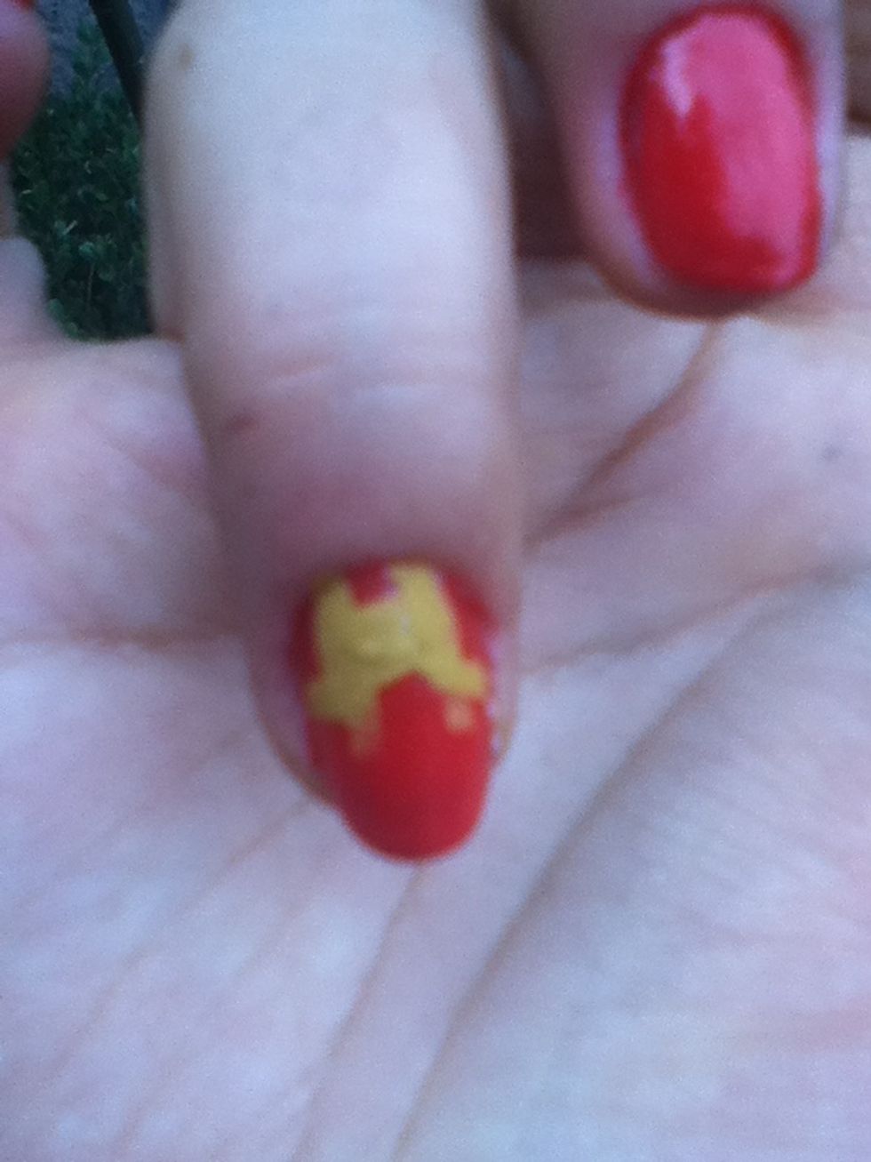 In your ring finger and your thumb your going to create the IRON MAN!! Using a yellow nail polish and a thin brush create two straight lines and two diagonal lines in each side!