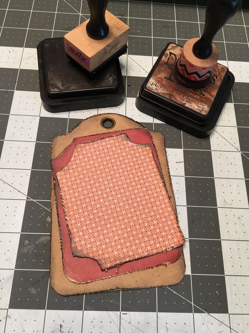 Ink all the edges and glue to the back side of the kraft tag, placing them at different angles with the smaller mat layered on top of the larger mat.