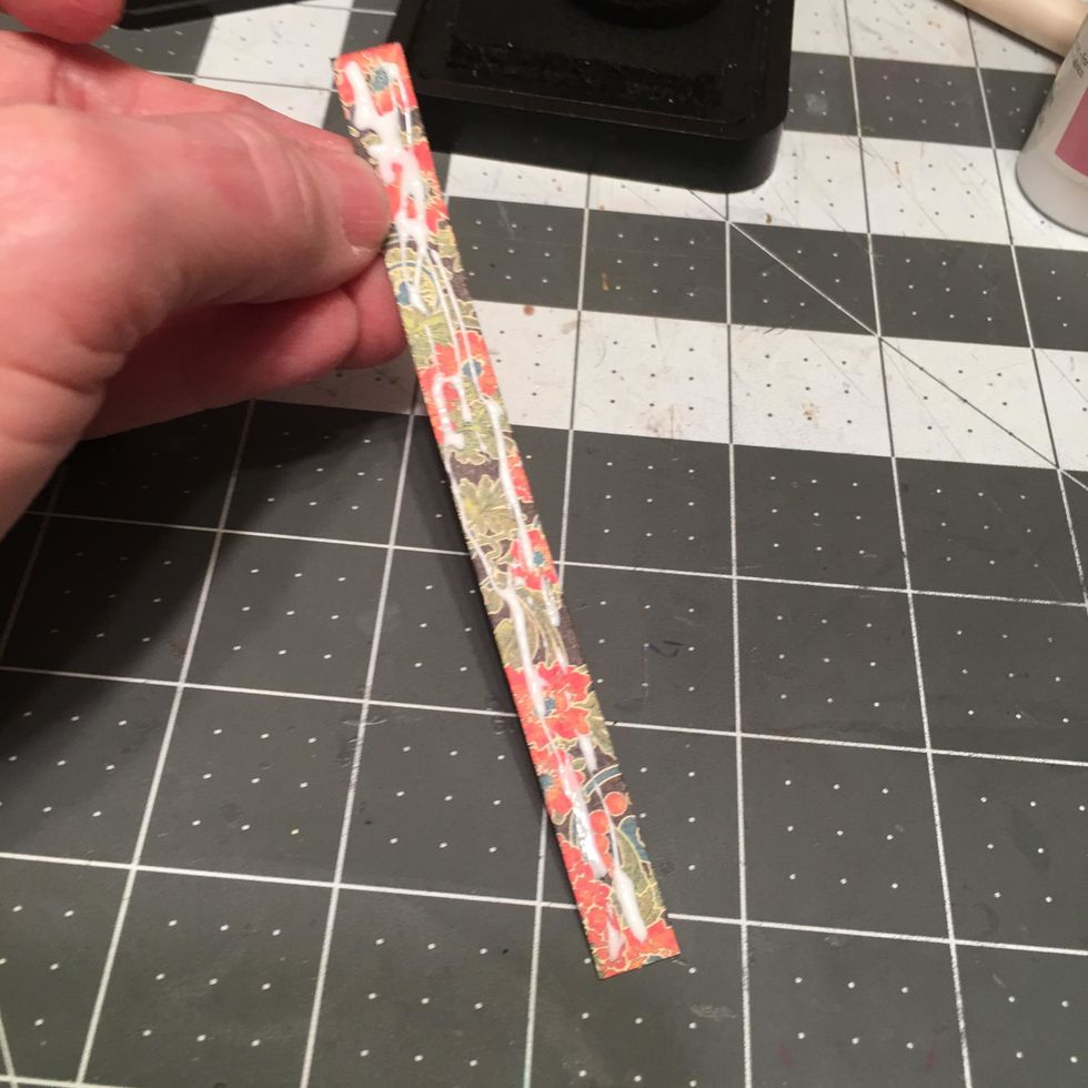 Ink the narrow strip of patterned paper you cut for the outside spine area of your album and apply glue to the back side.