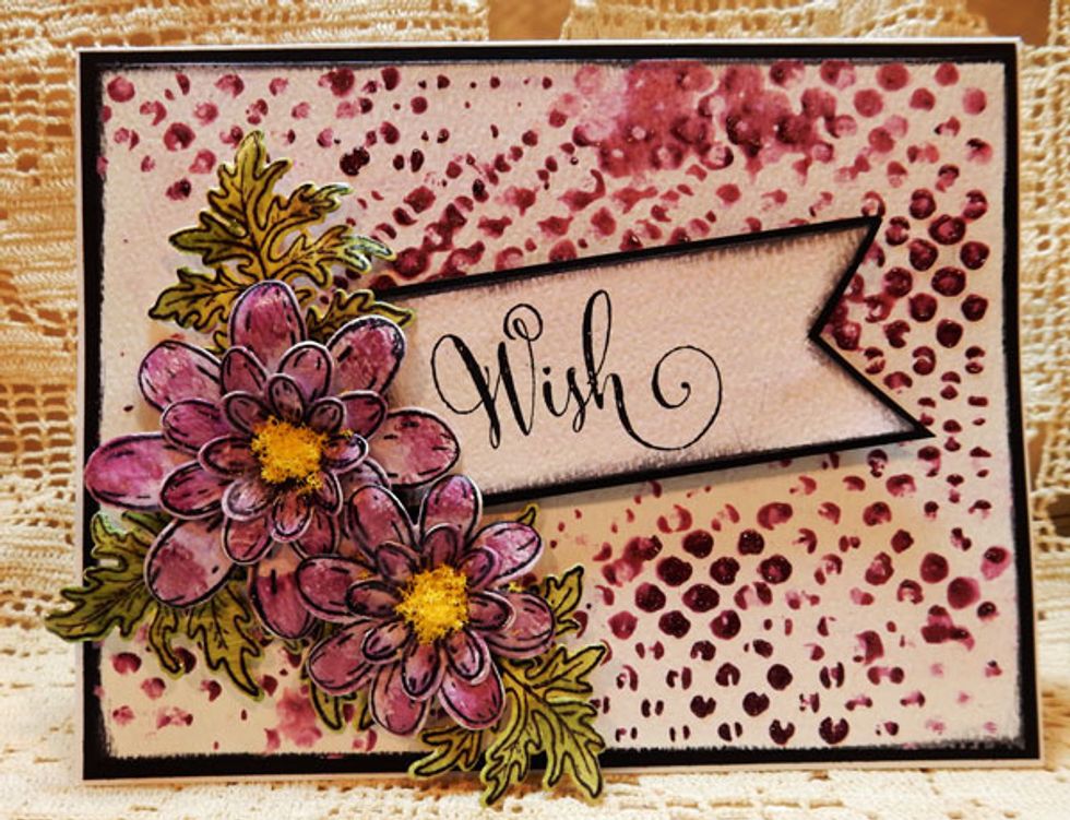 Ink the stenciled panel with black ink and mat with black cardstock. Assemble the daisies with brads. Add daisies and leaves to panel, adding foam adhesives where necessary. Add panel to card.