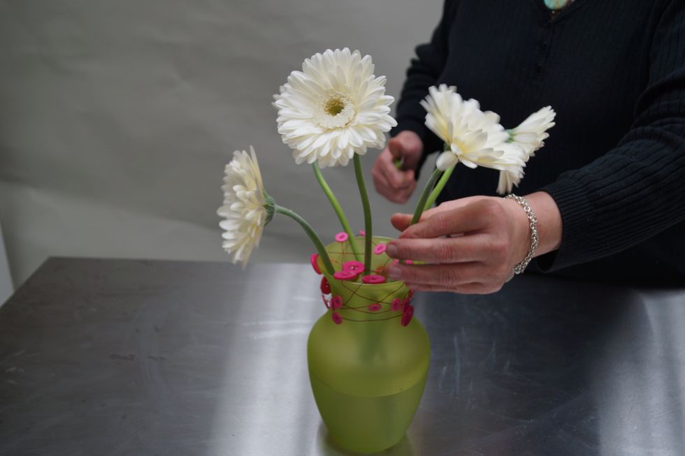 Insert gerberas in the wire grid - 4 around the vase and one in the center.